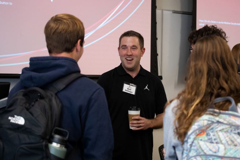 Person talks to two students.