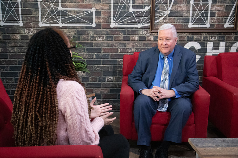 Andy Hall chats with McKenna Cardona sitting in armchairs.