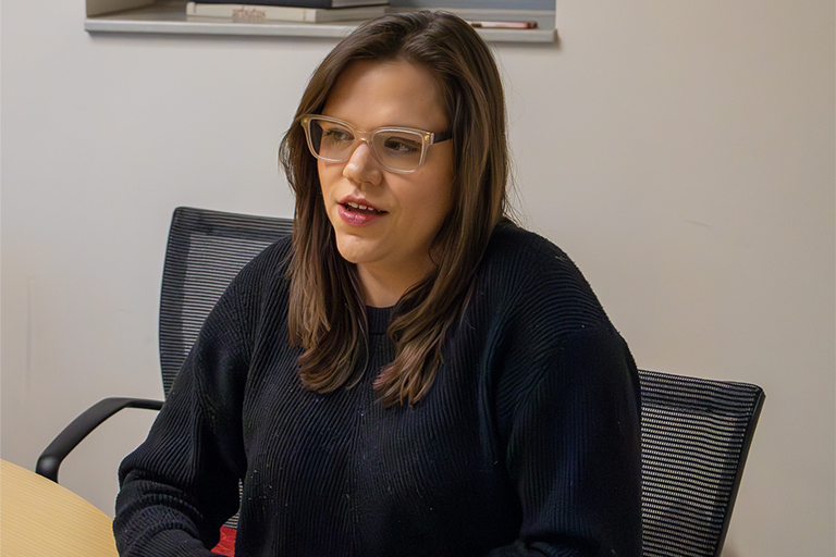 MJ Slaby sits at a table speaking.